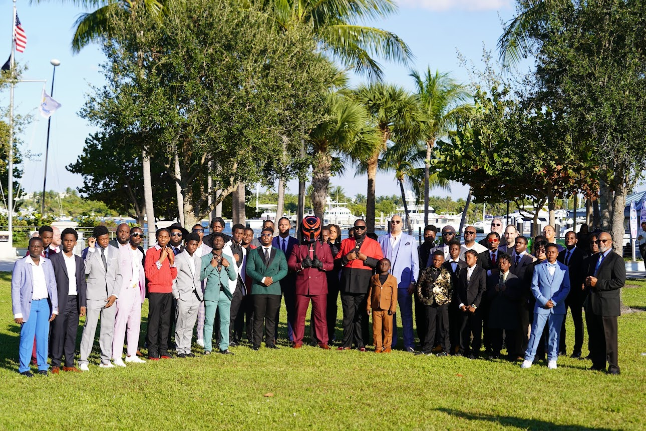 Young Men of Distinction participants and mentors gathered at a marina in formal attire during Takeover Weekend