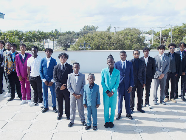 Large group of Young Men of Distinction participants in suits standing in an outdoor plaza